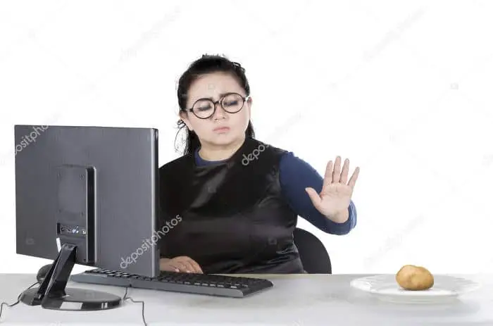 Woman ignoring potato while using computer.