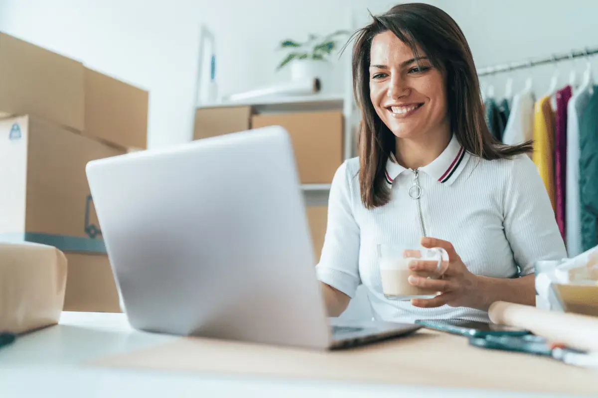 Woman working on laptop with coffee in office.