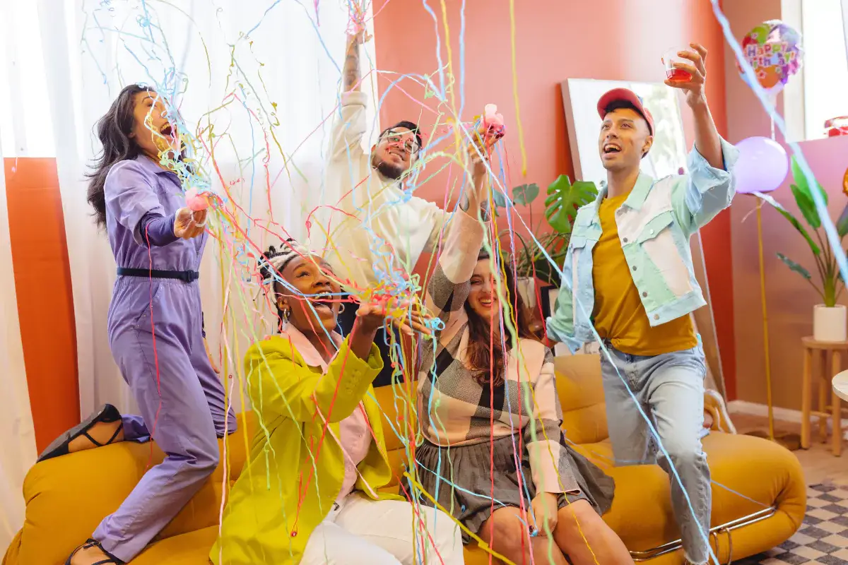 Friends enjoying colorful party streamers indoors.