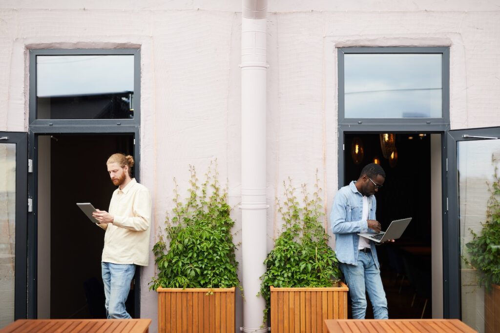 Two business people on tablets standing outside a building learning what they need to know before getting a website.