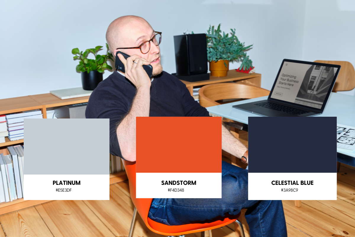An IT professional on the phone at his desk behind a graphic of three color swatches used on his IT services website.